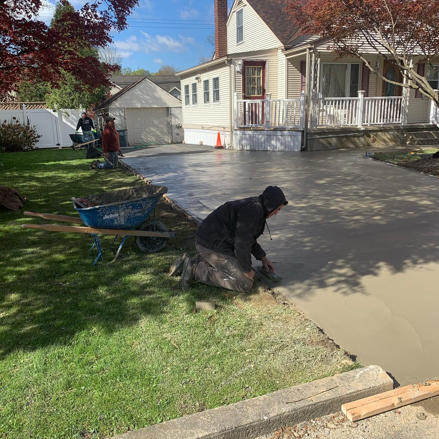 A man smoothing out concrete on a freshly poured driveway.
