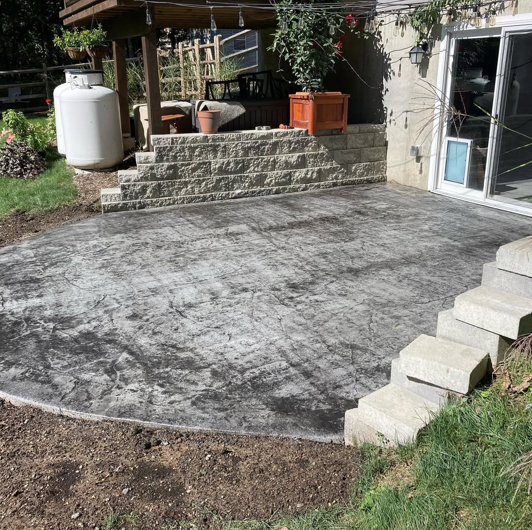 An area behind a house showcasing a stamped concrete patio.